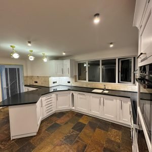 White resprayed kitchen with slate floor, corner view